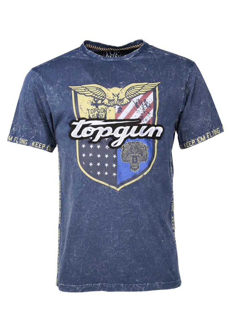 Granatowa koszulka z nadrukiem tarczy, na której znajduje się orzeł, paski i grafika lwa. Tekst zawiera "topgun" oraz "KEEP EM FLYING". Efekt przetarcia.