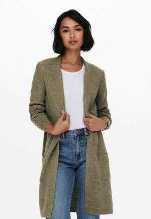 Olive green knitted cardigan with an open front, long sleeves, and two front pockets, worn over a white top and distressed denim jeans.