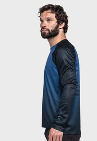 Langärmliges Sporthemd in einem Farbverlauf von Blau zu Schwarz, mit strukturiertem Stoff und Logodetails auf dem Ärmel.