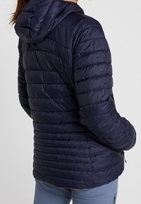 Navyblauer Pufferjacke mit Kapuze, die über eine gesteppten Struktur und leichte Isolierung verfügt, die für Wärme und Komfort sorgt. Mit Reißverschlusstaschen.