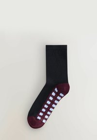 Musta sukka, jossa on maroonin ja valkoisen ruutukuosin pitävä pohja, joka on teksturoitu, polveen asti ulottuva ja saumaton muotoilu.