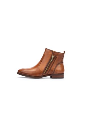 Bota de tobillo de cuero marrón con punta redondeada, cremallera lateral y un tacón bajo. Presenta una textura suave y un acento metálico decorativo.