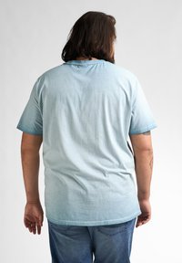Lyseblå kortærmet t-shirt med gradientdesign og blød tekstur. Bagsiden har en rund halsudskæring og en afslappet pasform.