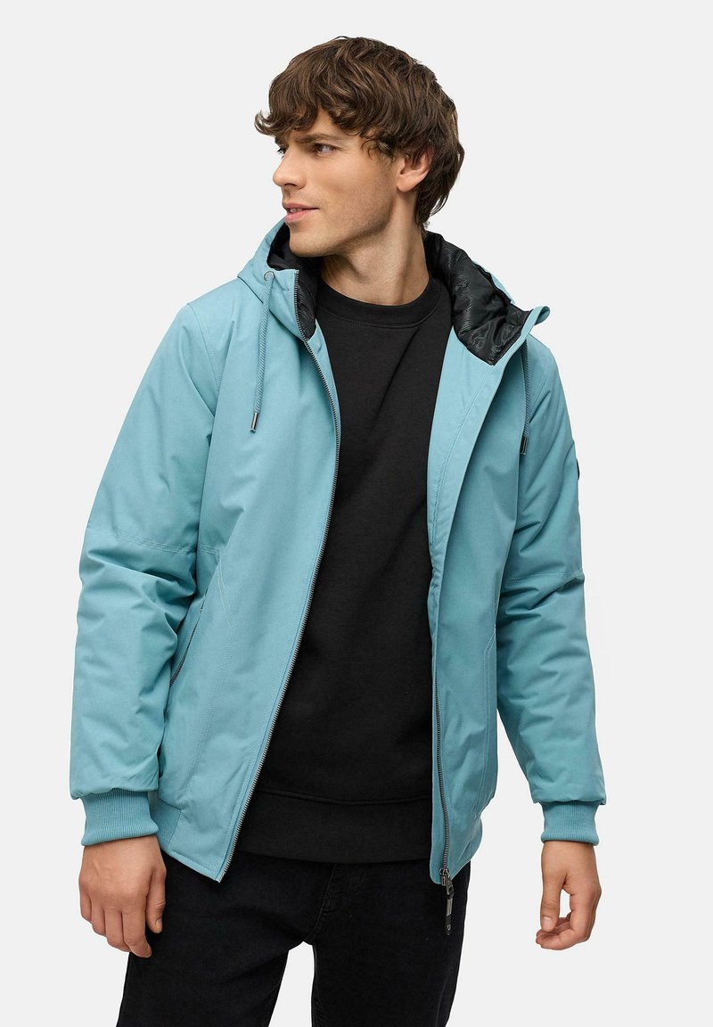 Ljusblå huva jacka med dragkedja fram, svart foder, ribbade ärmslut och en avslappnad passform. Har en enfärgad struktur och minimalistisk design.