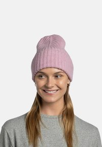 Pink knit beanie with a ribbed texture, featuring a rolled edge and a rounded top, worn by a person with long hair.