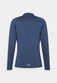 Långärmad marinblå teknisk skjorta med hög krage och flatlock-sömmar. Slät textur med en subtil varumärkesetikett vid fållen.