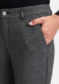 Szare w kratę spodnie uszyte z teksturowanej tkaniny, z przednią kieszenią i zapięciem na guzik w talii.