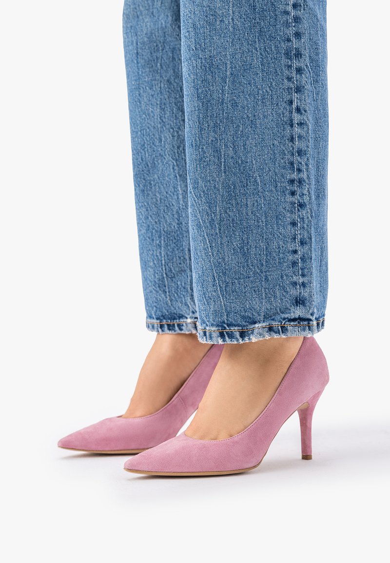 Jalad, mis kannavad lilla seemisnahast tipp-kontsaga kingi, kombineeritud siniste lühendatud teksapükstega, mille pikkus ulatub pahkluu kohale.