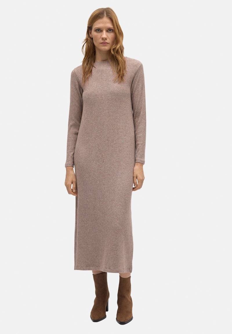 Vestido maxi de punto acanalado en marrón claro con mangas largas, cuello redondo y aberturas laterales. Combinado con botas de tacón marrón.