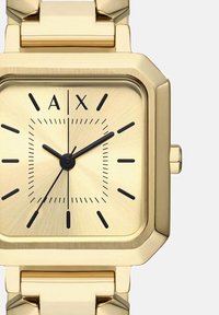 Goldfarbene quadratische Armbanduhr mit schwarzen Stundenmarkierungen, drei schwarzen Zeigern und dem "A|X" Logo an der 12-Uhr-Position.
