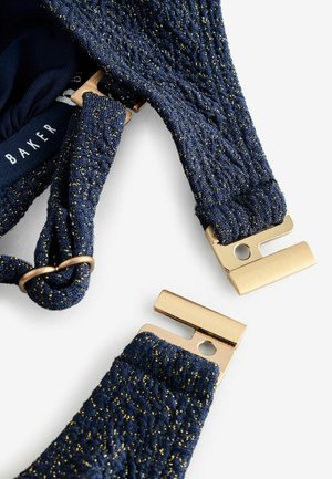 Marineblaue BH-Träger aus strukturiertem Stoff mit goldenen Sprenkeln, ergänzt mit goldenen Metallbeschlägen zur Anpassung und Befestigung.