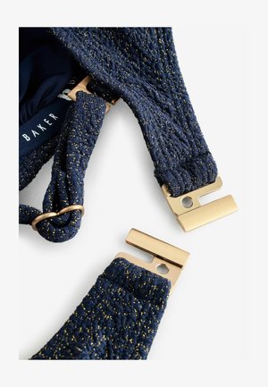 Jūras kara flotes krūštura siksnas ar teksturētu audumu, kurā ir zelta punkti, papildinātas ar zelta metāla aparatūru regulēšanai un piestiprināšanai.