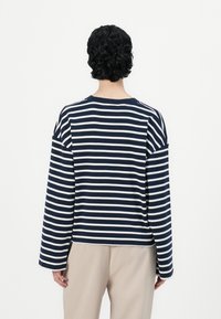 Top de manga larga a rayas azul marino y blanco, confeccionado en tejido suave. Presenta un escote redondeado y costuras de hombro caídas.