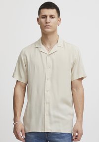 Kortermet, lys beige skjorte med knapper og krage, laget av glatt stoff, med en avslappet passform og minimalistisk design.