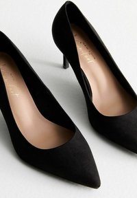 Tacchi alti in suede nero con punta affusolata e tacco stiletto sottile. Presentano una fodera interna liscia e un design minimalista.
