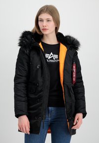 Crna podložena parka s kapuljačom obloženom krznom, narančastom unutrašnjosti, višestrukim gumbima sprijeda, bočnim džepovima i crvenom oznakom na rukavu.