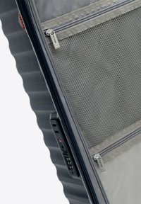 Hartschalengepäck in Marineblau mit strukturierten Rillen. Verfügt über Mesh-Taschen und silberne Reißverschlüsse. Enthält ein Zahlenschloss.