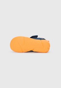 Blue sneaker sole with textured orange rubber, featuring a distinct wave pattern and brand logo imprinted on the surface.