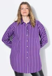 Camicia a righe viola con maniche lunghe, dotata di una tasca sul petto e un orlo curvo. Realizzata in tessuto morbido.