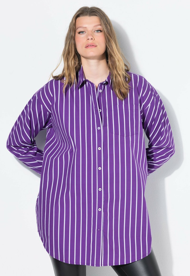 Camicia a righe viola con maniche lunghe, dotata di una tasca sul petto e un orlo curvo. Realizzata in tessuto morbido.