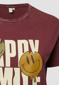 Bordowa bawełniana koszulka z luźnym krojem z dużą grafiką żółtej uśmiechniętej buźki i wyraźnym białym napisem "HAPPY". Gładka faktura.
