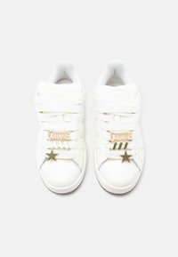 Λευκά αθλητικά παπούτσια Adidas Campus με χοντρές κορδόνια, χρυσά διακριτικά "Campus" και αστέρια σε κάθε παπούτσι, φωτογραφημένα από πάνω σε λευκό φόντο.