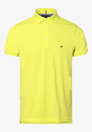 Koszulka polo z krótkim rękawem w neonowożółtym kolorze, z trzema białymi guzikami i małym logo Tommy Hilfiger na lewej stronie klatki piersiowej.