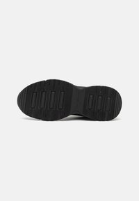 Suola di scarpa nera con un design del battistrada lavorato, caratterizzata da bordi arrotondati e scanalature rettangolari per una buona aderenza. Finitura della superficie liscia.
