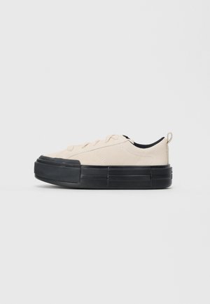 Madala heleda naturaalse värvi tenne, millel on paks must tald, paeltega eesmine osa, kanga tõmbeaas kandmisel ja must sisemine vooder.