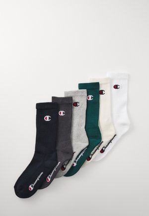 Seks par ribbede sokker i marineblå, kullgrå, grå, mørkegrønn, krem og hvit, hver med et logo og kontraststing ved kanten.