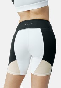 Shorts de sport taille haute avec un design en blocs de couleur noir, blanc et beige, dotés de coutures contrastantes et d'une texture lisse.