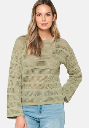 Light olive green knitted sweater featuring a striped open mesh design, long sleeves, and a ribbed neckline and hem. Paired with light blue jeans.