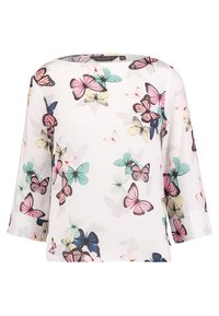 Blouse blanche ornée d'un imprimé papillon coloré dans des teintes de rose, bleu et vert. Elle possède des manches trois quarts et une coupe décontractée.