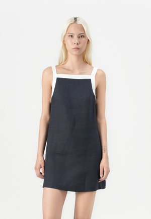 Robe sans manches bleu marine avec un décolleté carré et des bretelles blanches. Le tissu semble lisse avec un léger éclat, et il a une coupe décontractée.