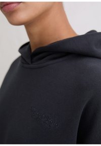 Marineblauwe capuchontrui met een zachte textuur, met een subtiel logo in een bijpassende kleur op de borst. Ontworpen met een ontspannen pasvorm.