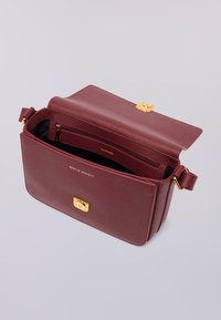 Borsa a tracolla in pelle bordeaux con hardware dorato, chiusura magnetica e tasca interna con zip. Superficie liscia al tatto, forma rettangolare.