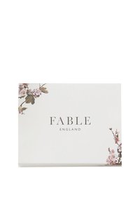 Bijela kutija s tekstom "FABLE ENGLAND" u sredini, ukrašena ilustracijama ružičastog i bijelog cvijeta trešnje u gornjem lijevom i donjem desnom kutu.
