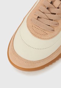 Ανδρικό αθλητικό παπούτσι από σουέντ σε ανοιχτό καφέ χρώμα με επίστρωση από κρεμ δέρμα, με ραμμένες λεπτομέρειες και επίπεδα κορδόνια. Διάφανη σόλα από καουτσούκ.