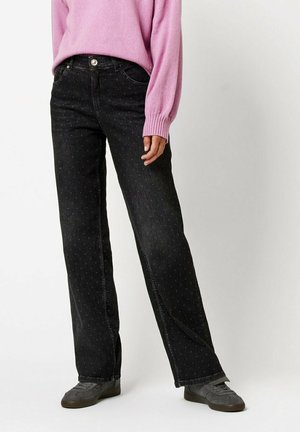 Black denim jeans with a straight leg, featuring a dotted pattern, five-pocket design, and a silver button closure. Paired with a pink sweater.