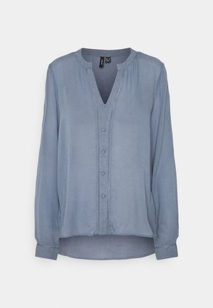 Hellblaue Bluse mit langen Ärmeln, Knopfleiste vorne, Stehkragen und subtilen Nähten entlang der Knopfleiste und Manschetten.