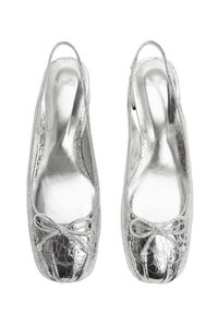 Srebrne metaliczne płaskie buty z okrągłym noskiem, z kokardą z przodu i błyszczącym, teksturowanym wykończeniem. Model z odkrytą piętą i zapięciem na zapiętek.