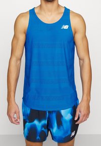 Blå atletisk ärmlös tröja med texturerade ränder och en logotyp, kombinerad med svarta shorts med ett blått abstrakt mönster. Lättviktig tyg.