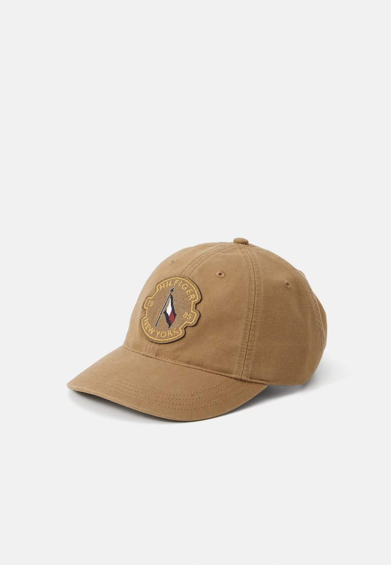 Brown cotton baseball cap with a rounded crown, curved brim, and embroidered logo featuring a sailboat and text, on the front panel.