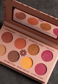 Paleta cieni do powiek z dziewięcioma okrągłymi wkładkami w ciepłych odcieniach: miedź, pomarańcz, róż i złoto. Teksturalne i matowe wykończenia w dekoracyjnym opakowaniu.