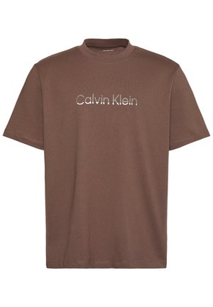 T-shirt marron à manches courtes et col rond avec un logo "Calvin Klein" argenté réfléchissant centré sur la poitrine.