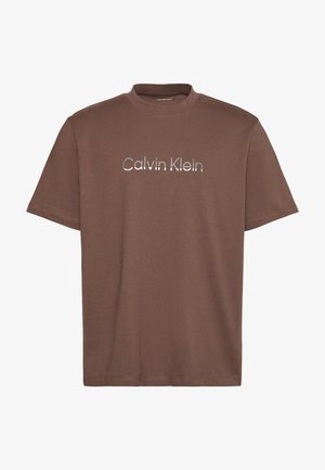 Hnědé tričko s krátkými rukávy a kulatým výstřihem s reflexním stříbrným logem "Calvin Klein" umístěným uprostřed na hrudi.