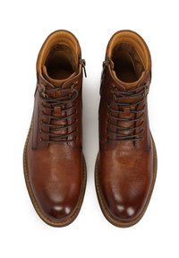 Botas de cuero marrón hasta el tobillo con un acabado texturizado, punta redonda, cordones en la parte delantera, cremalleras internas y forro acolchado en color tan. Suela de goma con detalle de costura.