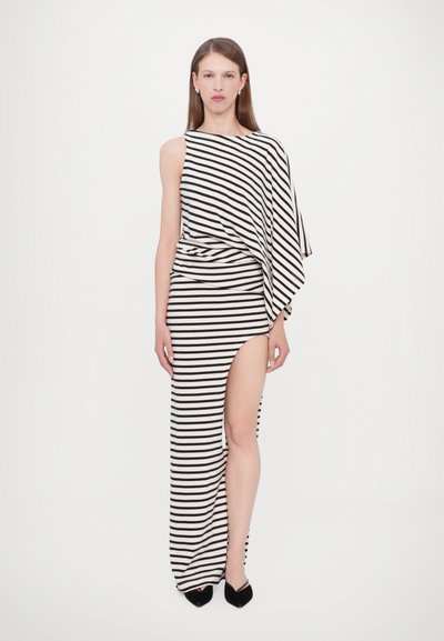 Maxi dress with asymmetric design in black and white stripes, featuring a high slit and draped fabric. Soft texture, sleek silhouette, and sleeveless.