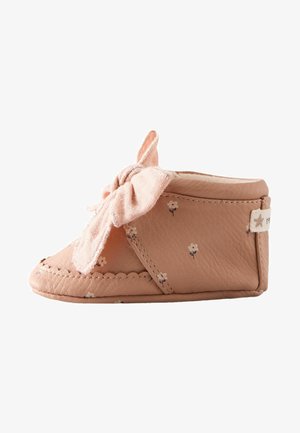 Zachten roze leren babyschoen met een klein bloemenpatroon, ronde neus en een opvallende stoffen strik aan de voorkant. Gelaagd oppervlak en gestikte rand.