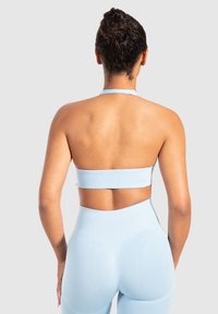Soutien-gorge sport azzurro chiaro con design a collo alto, caratterizzato da una texture morbida e rigata e una fascia larga; abbinato a leggings a vita alta.